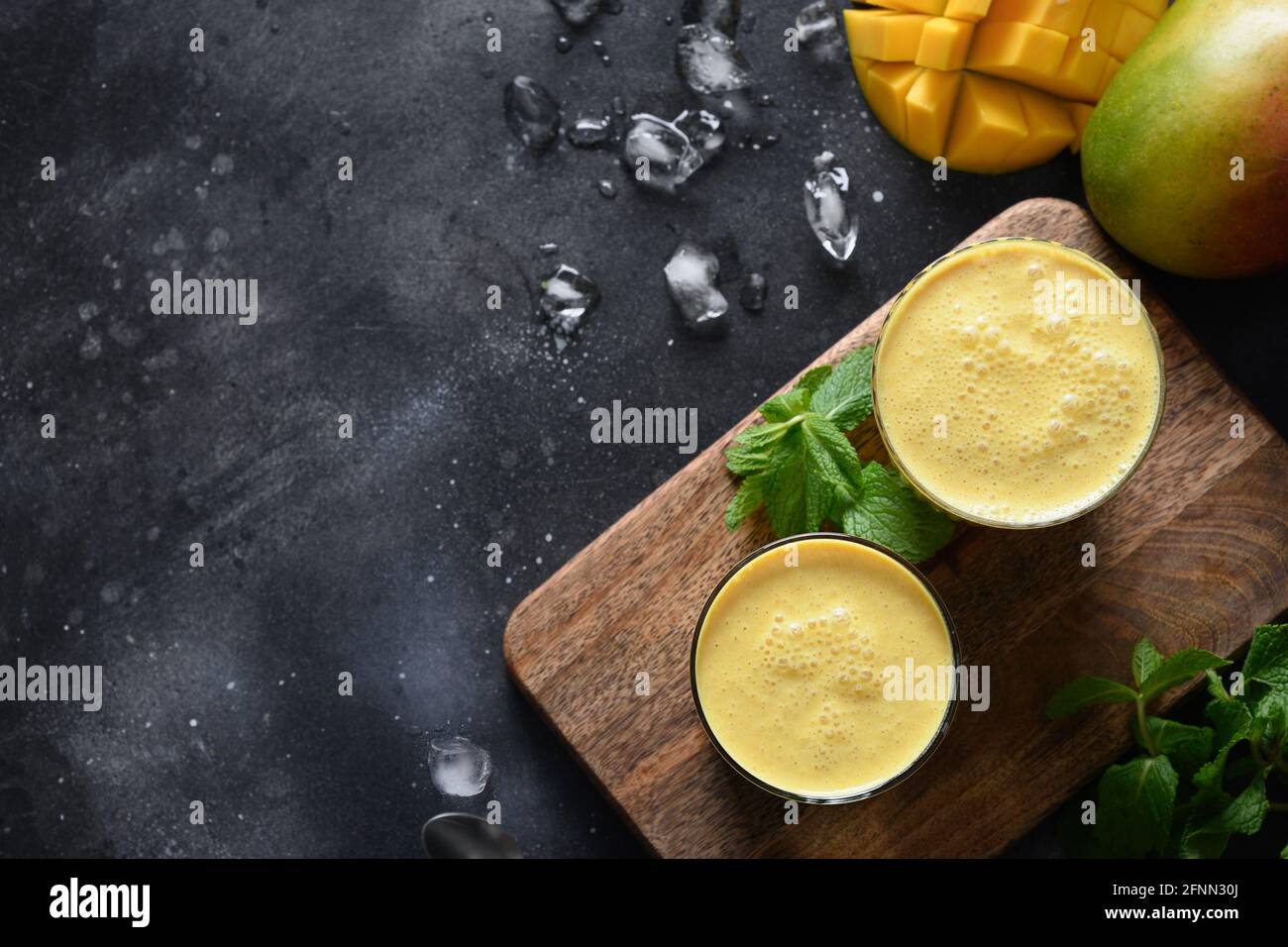 Deux lassi Mango ou smoothies sur fond noir, vue de dessus avec espace de copie. Lassi traditionnel indien de mangue froide fait de yaourt, eau, épices, fruits Banque D'Images