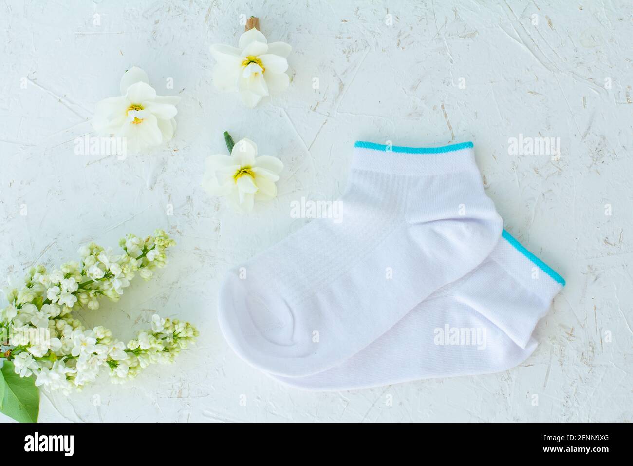 Paire de femmes chaussettes et bourgeons de fleurs de jonquille sur le fond blanc structuré, vue du dessus. Banque D'Images