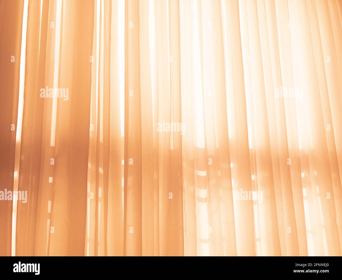 Le soleil brille à travers les rideaux orange doux Banque D'Images