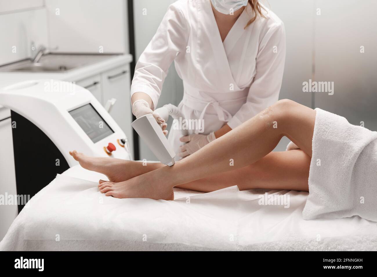 Clinique de beauté et concept de soins du corps. Esthéticienne au salon de  spa utilisant un appareil d'épilation laser sur les jambes, mannequin  allongé sur une table de thérapie pendant que maître
