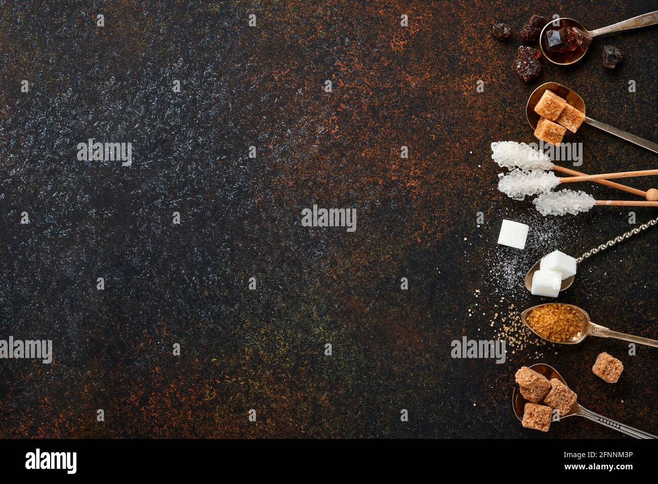 Sucre blanc, cubes de sucre de canne, caramel en cuillères à café sur fond de béton de table brun foncé. Différents types de sucre assortis. Vue de dessus ou plan de travail. Banque D'Images