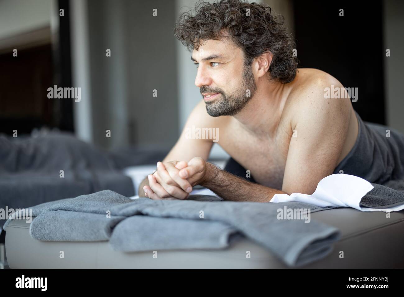 Bel homme allongé dans un salon de spa, qui attend un massage du dos et une relaxation. Le bien-être et les loisirs pour les soins de santé ensemble. Concentrez-vous sur l'homme. Regardez la caméra. Banque D'Images