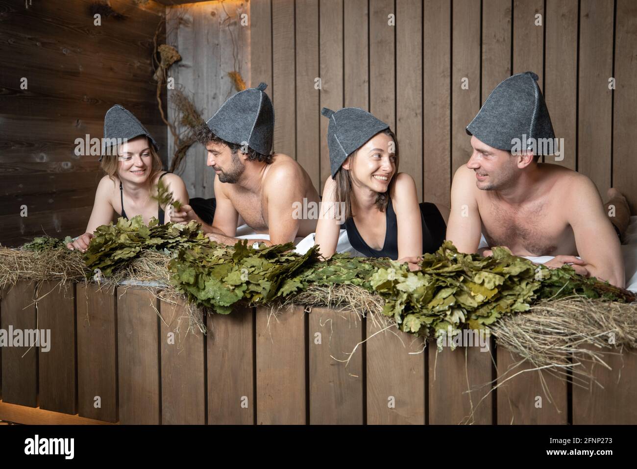 Compagnie d'amis couché sur banc de bois couvert de foin dans le sauna  traditionnel russe dans les chapeaux de sauna. Bien-être et loisirs au spa  Photo Stock - Alamy