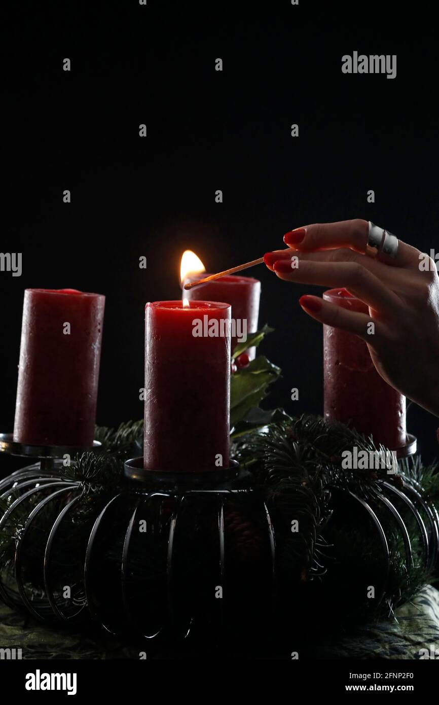 Couronne ou couronne de l'Avent. Femme lignant des bougies rouges. Composition de Noël. France. Banque D'Images