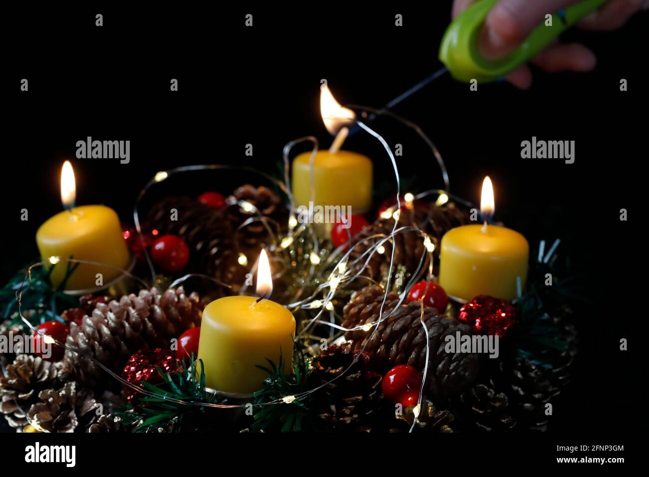 Couronne ou couronne de l'Avent. Femme lignant des bougies jaunes. Composition de Noël. France. Banque D'Images
