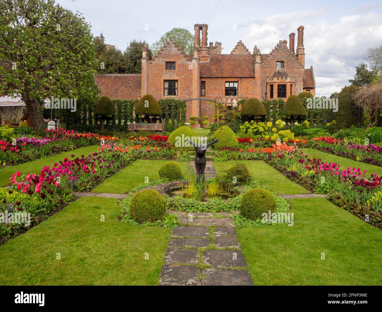 Chenies Manor House et jardin en contrebas en mai 2021, montrant le magnifique affichage de tulipes colorées de fleurs rouges, orange, pourpres et pelouse verte luxuriante. Banque D'Images
