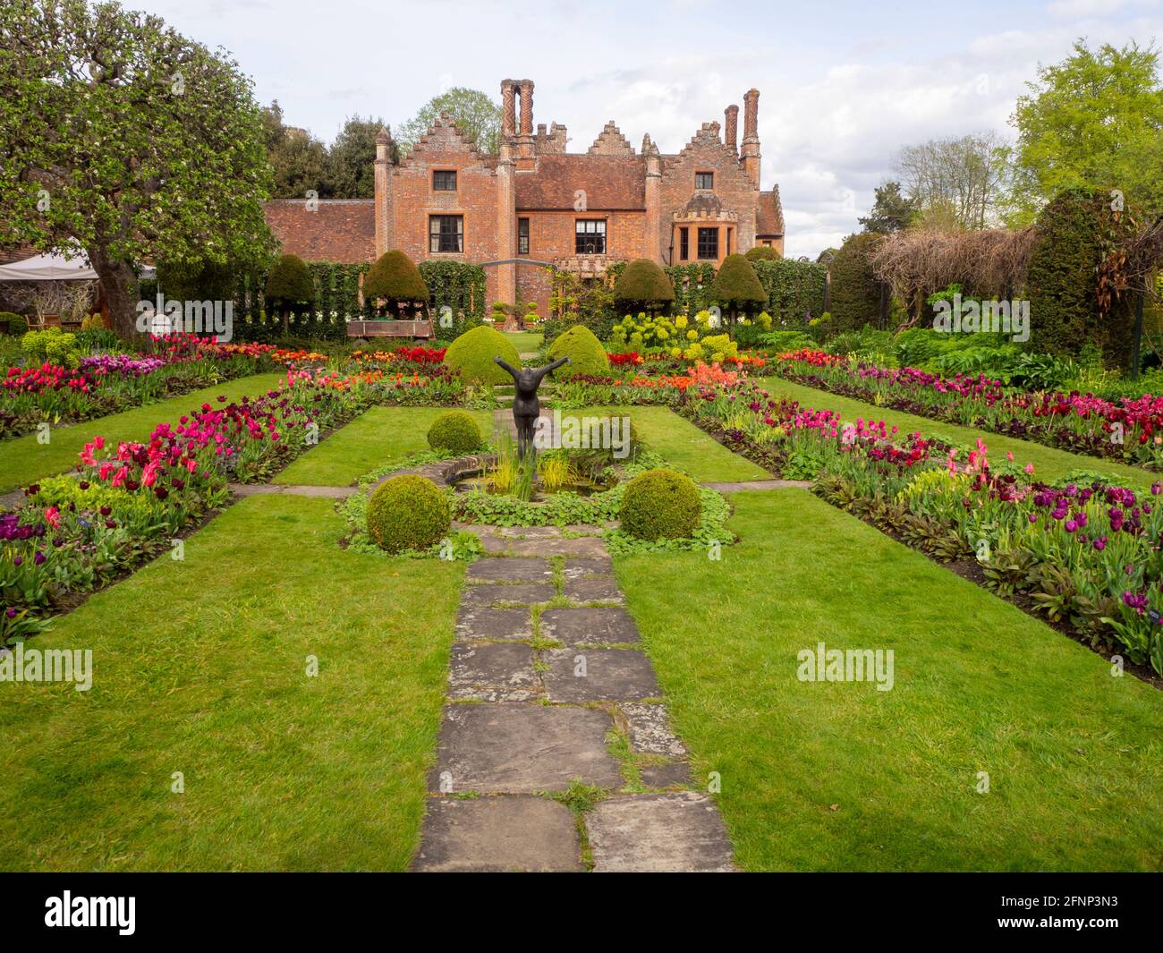 Chenies Manor House et jardin en contrebas en mai 2021, montrant le magnifique affichage de tulipes colorées de fleurs rouges, orange, pourpres et pelouse verte luxuriante. Banque D'Images