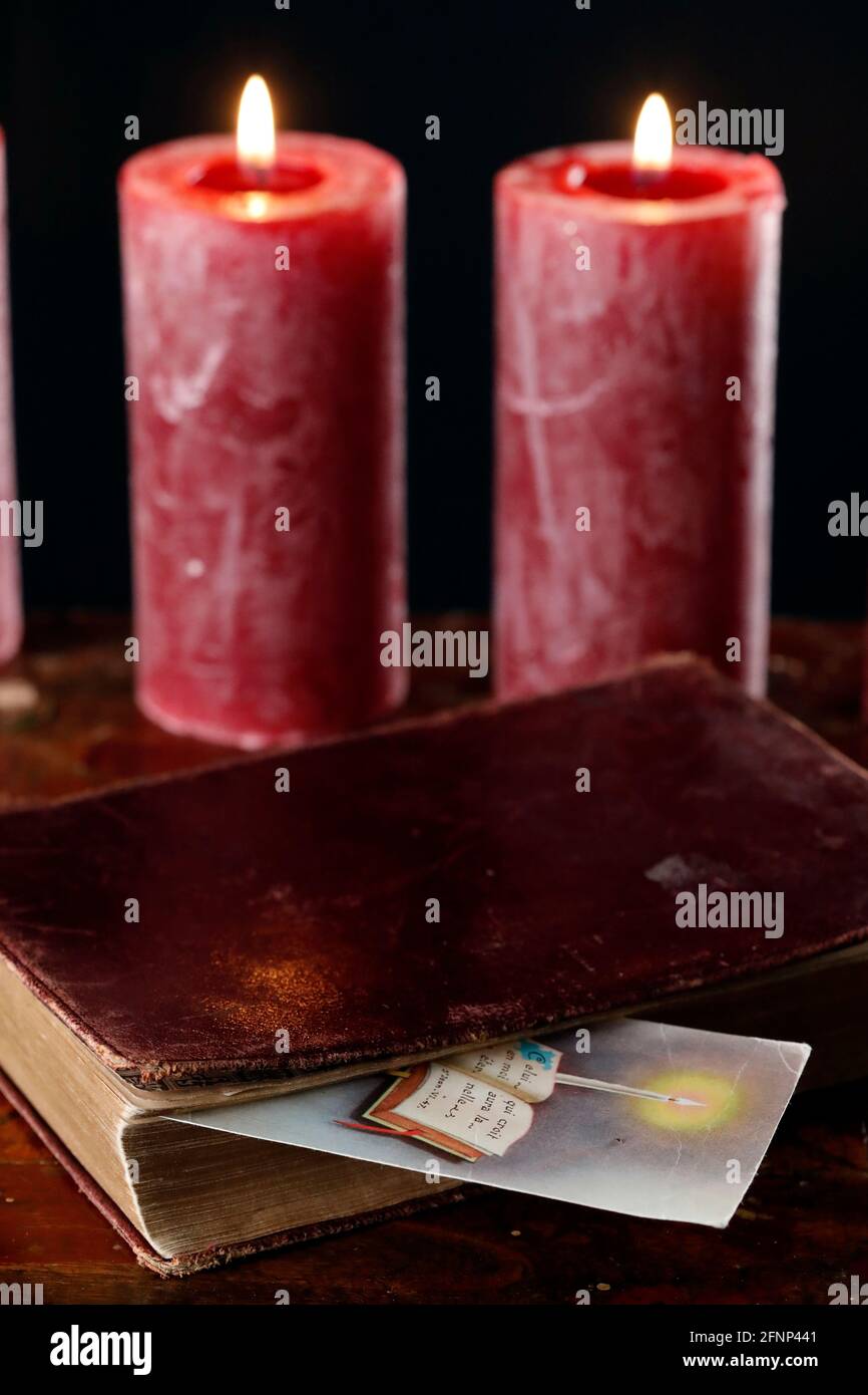 Vieille bible, image religieuse et deux bougies rouges brûlantes. France. Banque D'Images