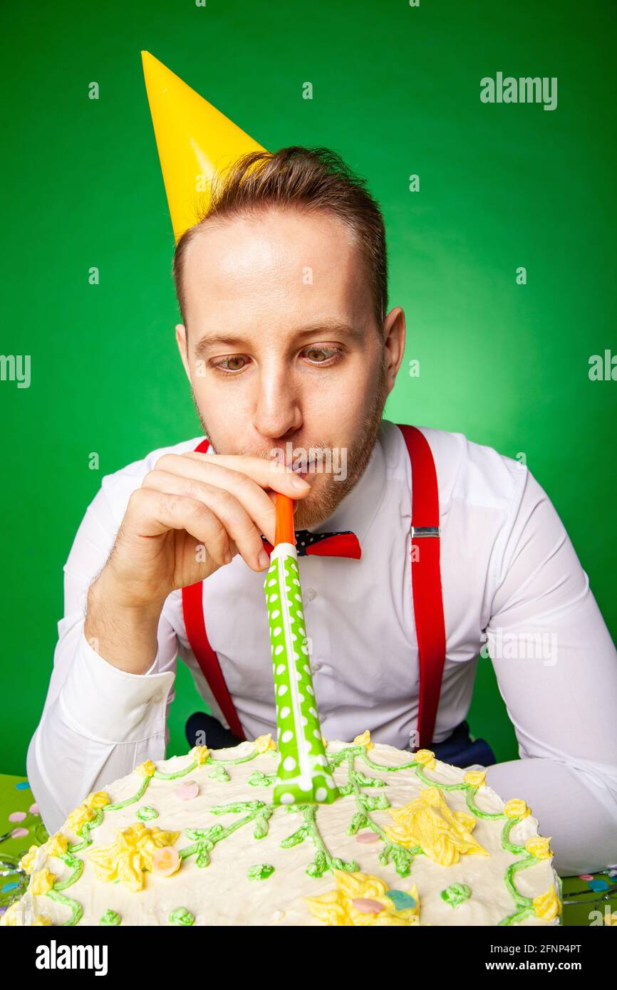 Homme En Fete Chapeau Assis A Table Avec Un Joyeux Anniversaire Gateau Et Souffleur De Bruit Sur Le Fond Vert En Studio Photo Stock Alamy