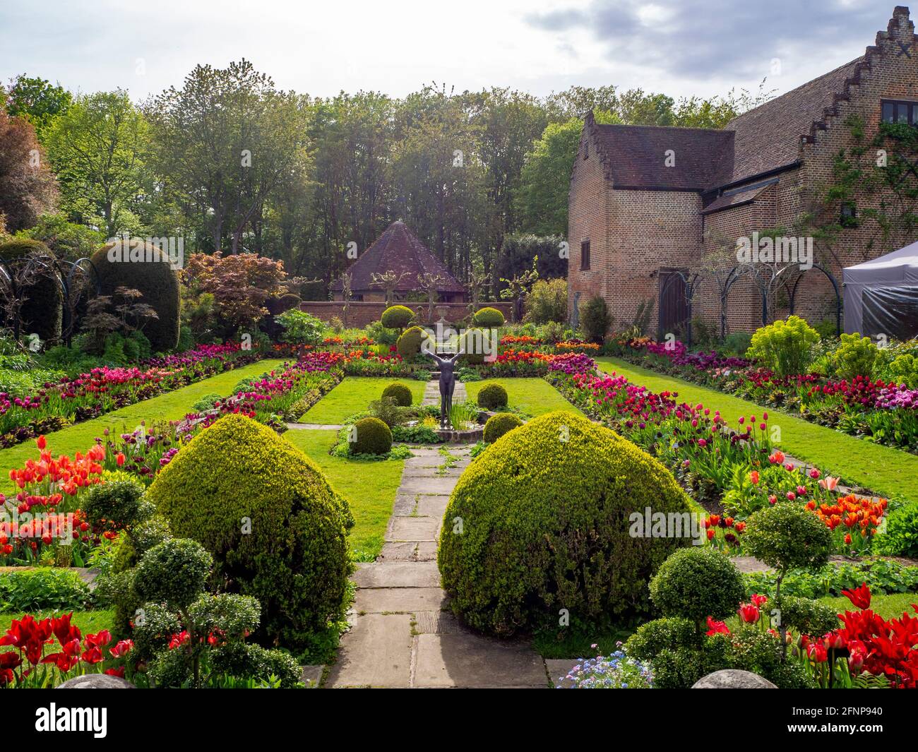Chenies Manor jardin en contrebas dans la lumière de la fin de l'après-midi, orienté vers l'ouest. L'ancien pavillon restauré est un décor de tulipes colorées d'orange, de rouge et de pourpre. Banque D'Images