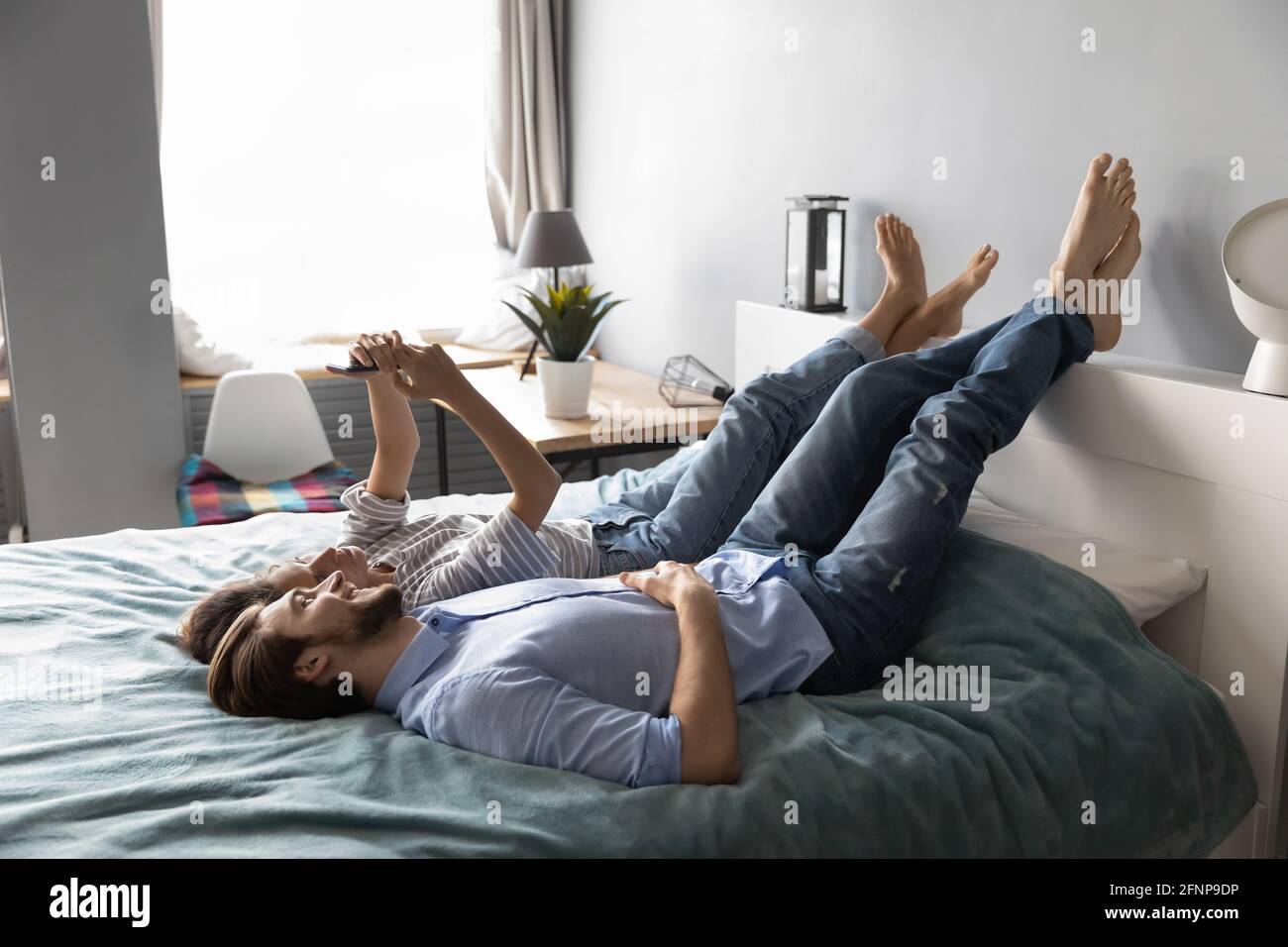 Couple heureux détendez-vous dans la chambre à l'aide d'un smartphone Banque D'Images