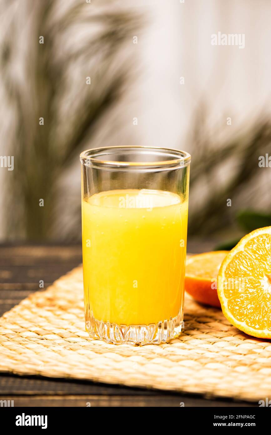 Un verre de jus d'orange frais sur un tapis de paille et une table en bois. Jour  d'été ensoleillé et branches de palmier Photo Stock - Alamy