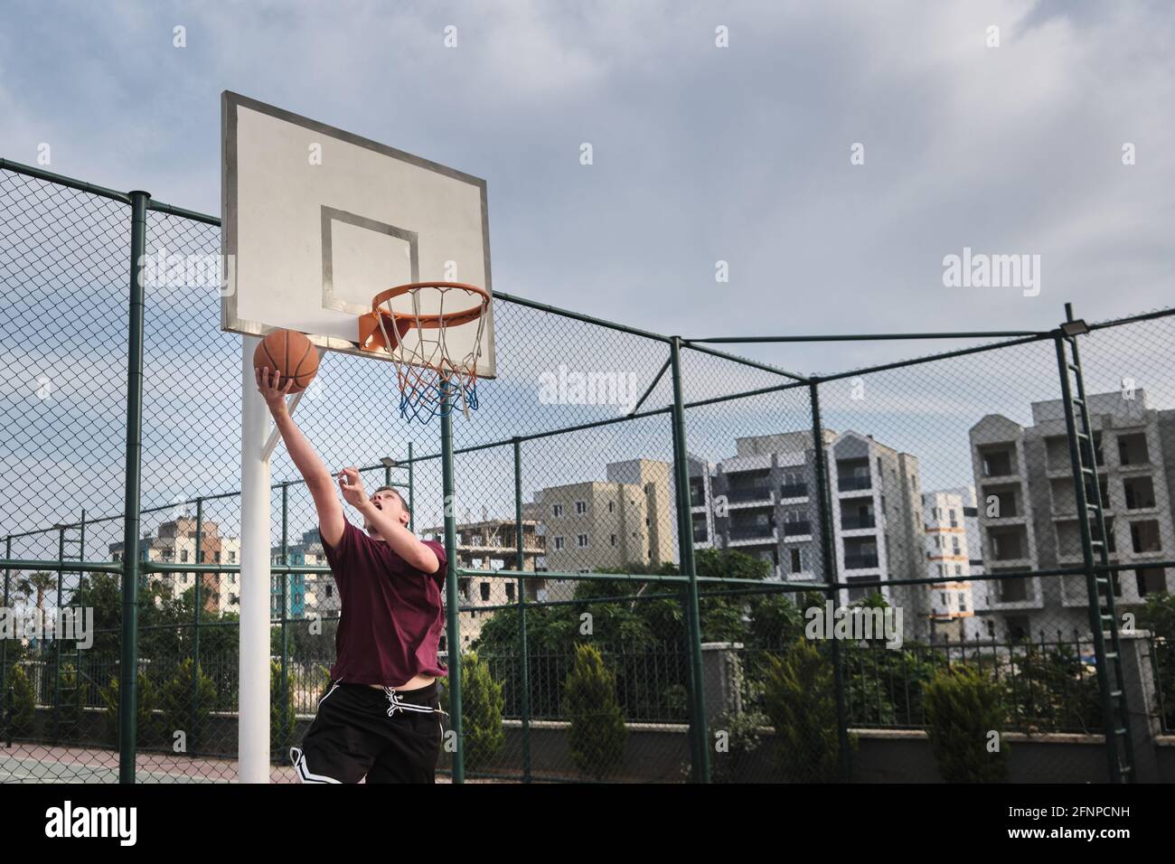 L'homme joue au basket-ball sur le terrain extérieur Banque D'Images