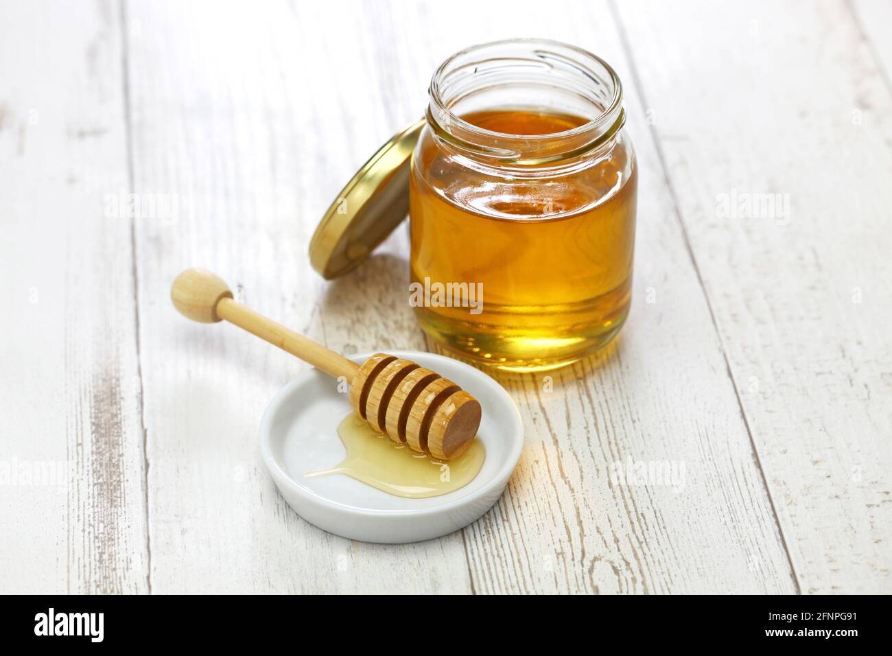 miel dans un pot en verre avec un balancier en bois de miel Banque D'Images