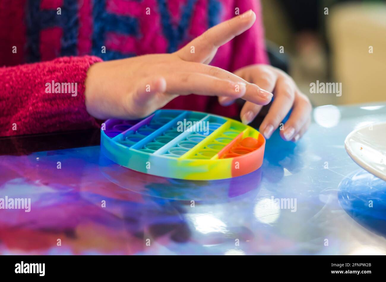 Jouet anti-stress pour enfants en silicone pour le développement tactile. Photo des mains des enfants sur un arrière-plan flou. Banque D'Images