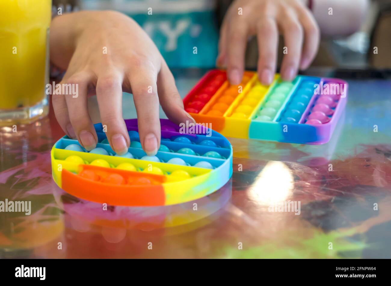 Jouet anti-stress pour enfants en silicone pour le développement tactile. Photo des mains des enfants sur un arrière-plan flou. Banque D'Images