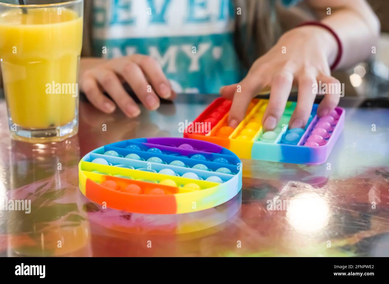 Jouet anti-stress pour enfants en silicone pour le développement tactile. Photo des mains des enfants sur un arrière-plan flou. Banque D'Images