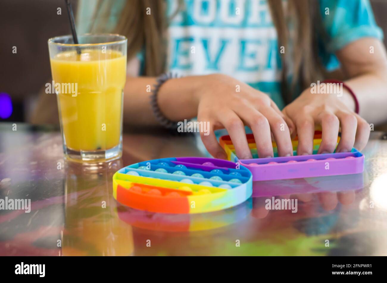 Jouet anti-stress pour enfants en silicone pour le développement tactile. Photo des mains des enfants sur un arrière-plan flou. Banque D'Images