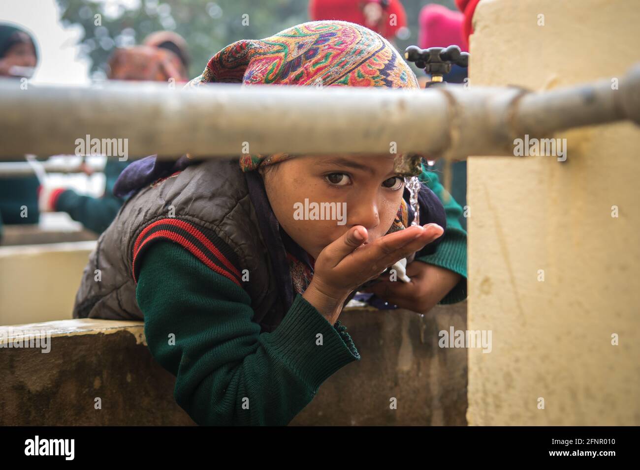 Uttar Pradesh, Inde. 05-11-2019. Une jeune femme indienne se rince la bouche après le déjeuner avant de retourner à l'école. Banque D'Images