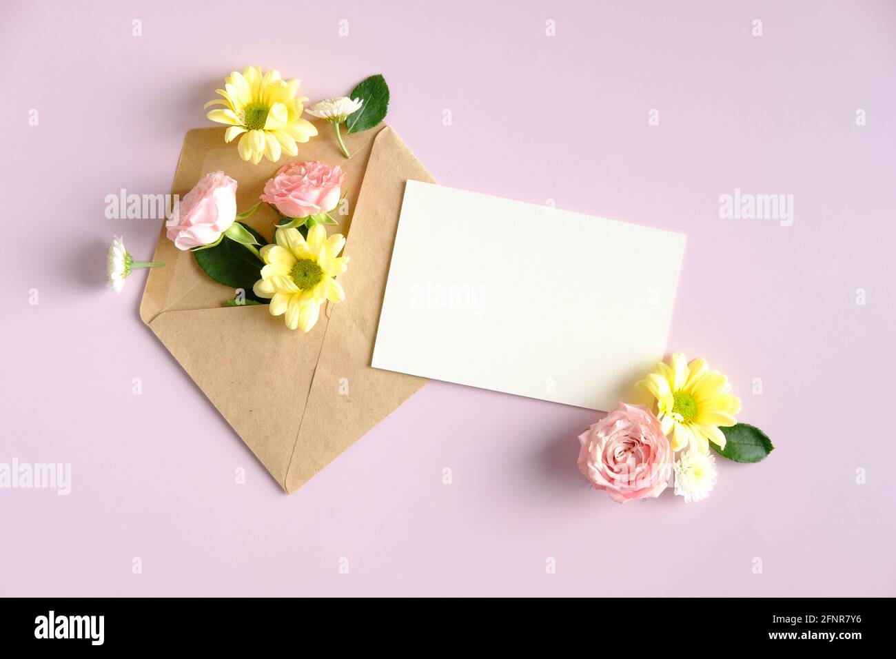 Ouvrez l'enveloppe avec des fleurs et une carte papier vierge sur fond rose. Romantique, concept de lettre d'amour. Banque D'Images