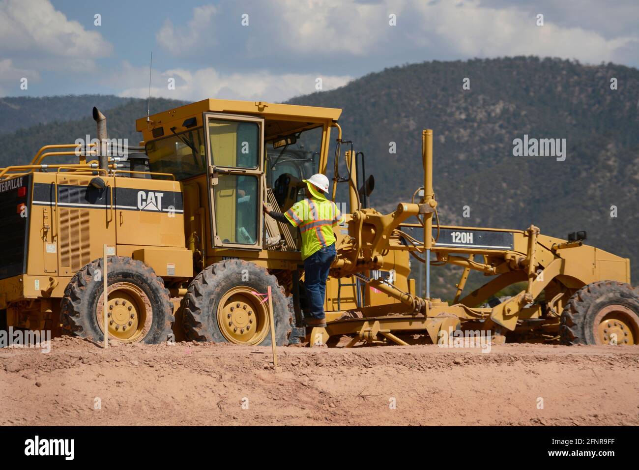 Un conducteur d'équipement lourd utilise une niveleuse Caterpillar 120H pour déplacer la terre sur un chantier de construction de routes à Santa Fe, Nouveau-Mexique. Banque D'Images