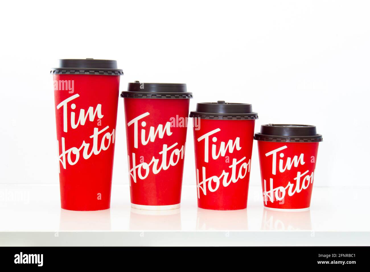 Calgary, Alberta, Canada. 18 mai 2021. Tasses de café Tim Hortons de différentes tailles sur une table blanche. Banque D'Images