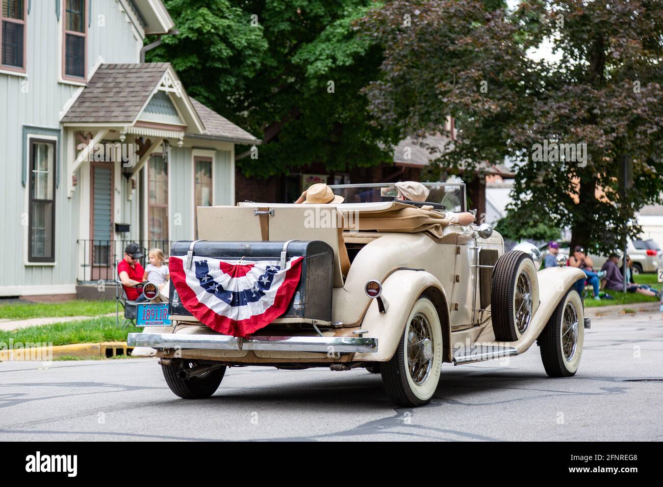 Un roadster antique d'Auburn traverse Auburn, dans l'Indiana, tout en affichant un bourdon patriotique dans le défilé du festival Auburn Cord Duesenberg 2019. Banque D'Images