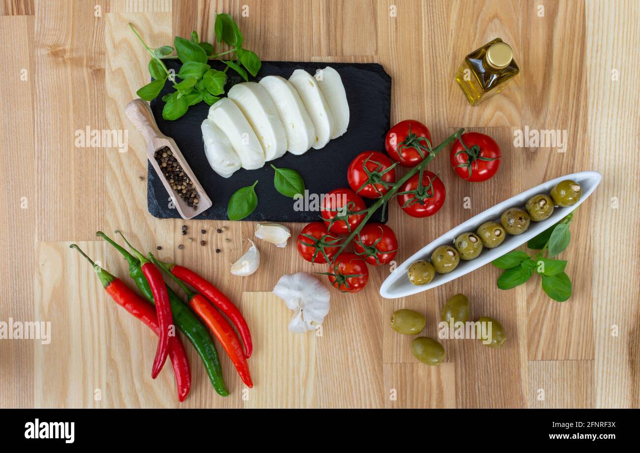 Photographie alimentaire, spécialités italiennes : tomates, olives, poivre, mozzarella, ail, persil. Banque D'Images