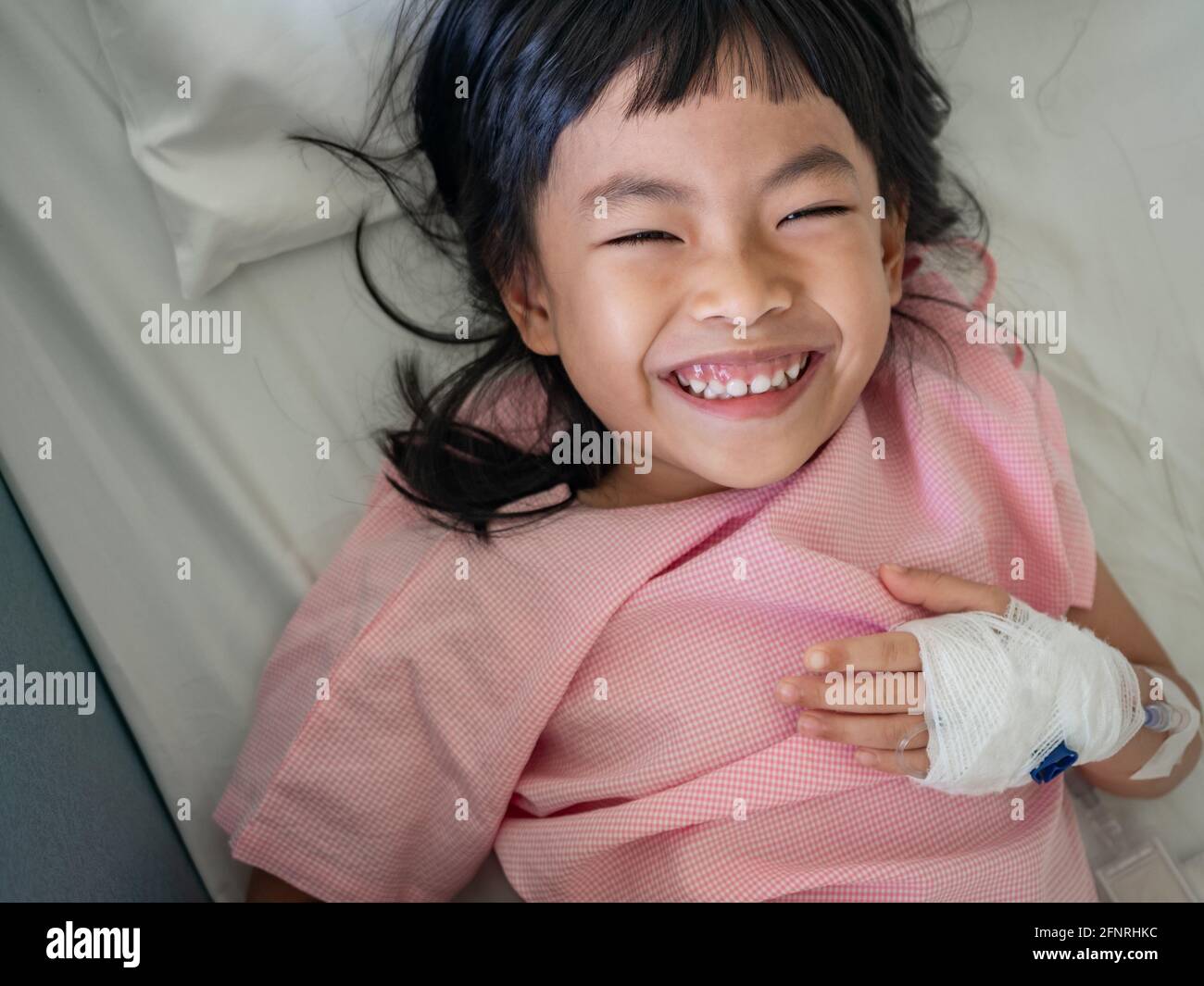 Fille asiatique sur le lit de l'hôpital avec humeur positive. Grand sourire sur le lit. Banque D'Images