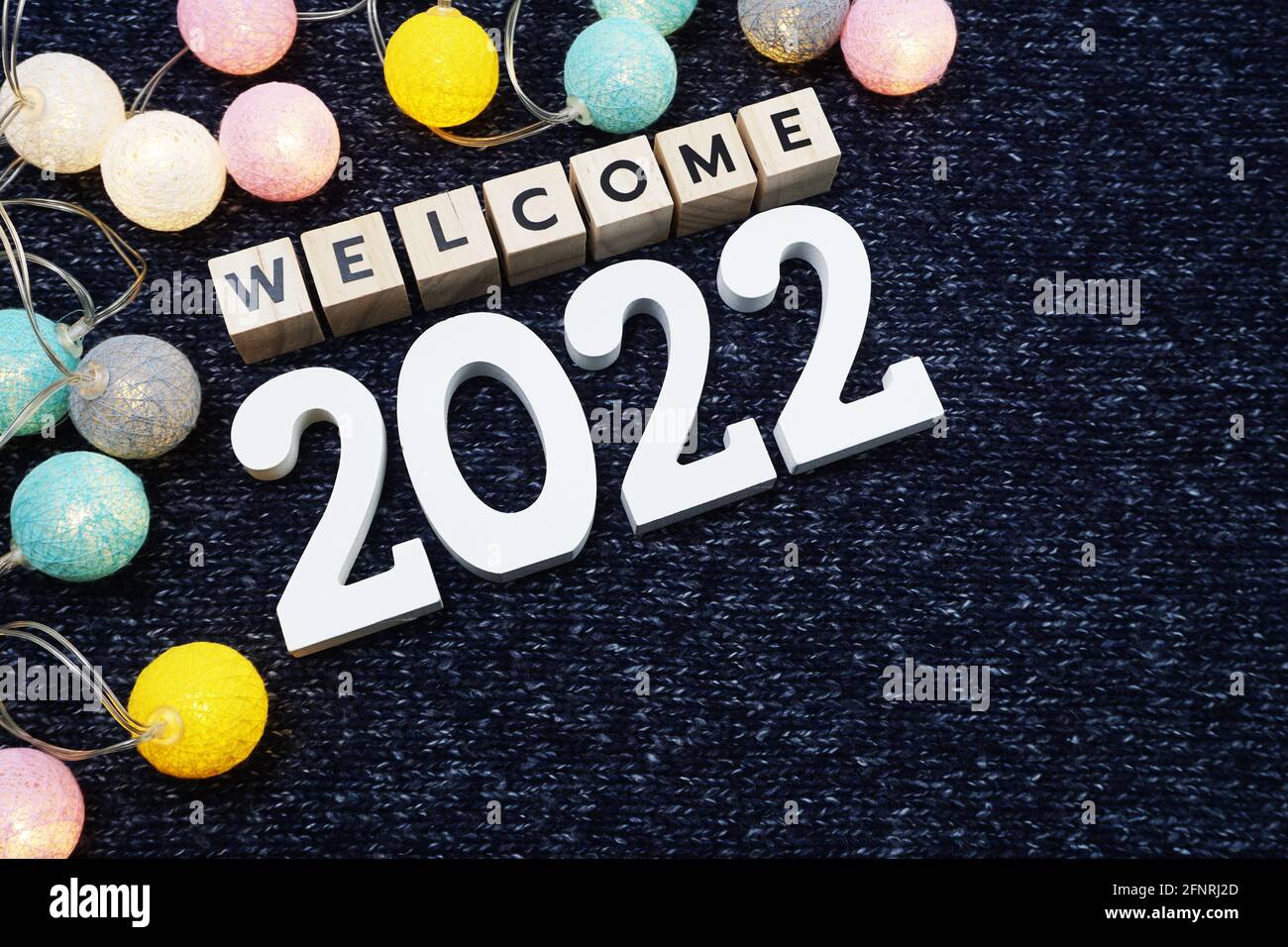 Bienvenue lettre de l'alphabet 2022 avec boule de coton LED sur fond de tissu tricoté bleu Banque D'Images