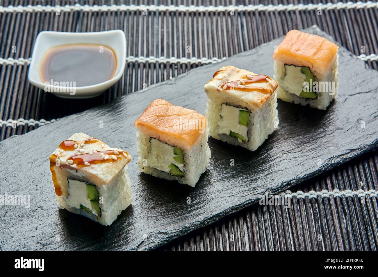 Philadelphie avec un concombre sur une pierre sombre. Sushi japonais. Banque D'Images