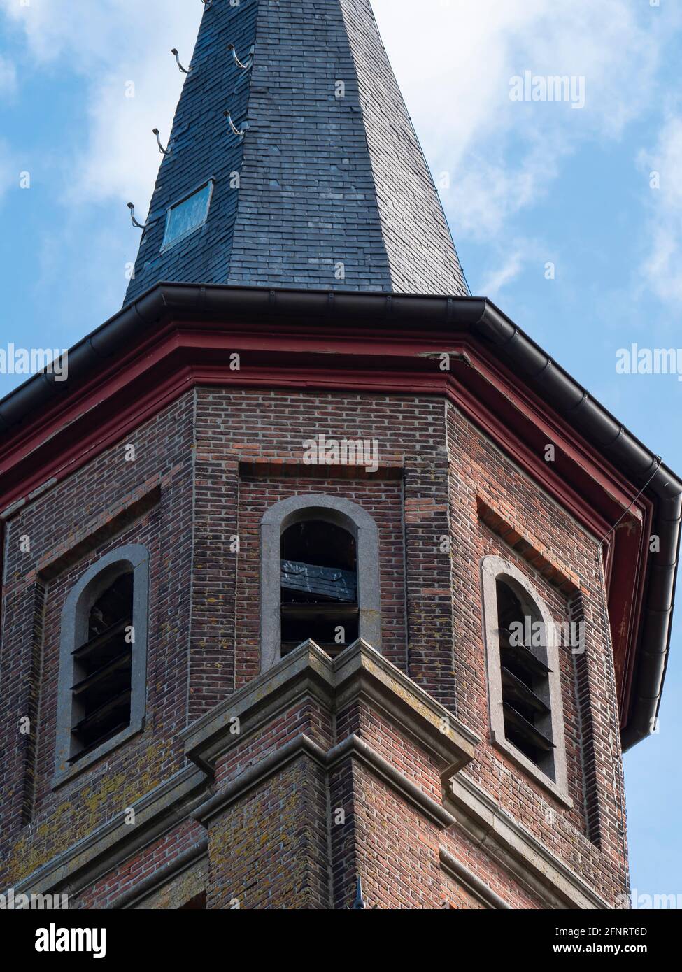 Gros plan d'une tour d'église en brique avec ciel bleu et des nuages blancs Banque D'Images