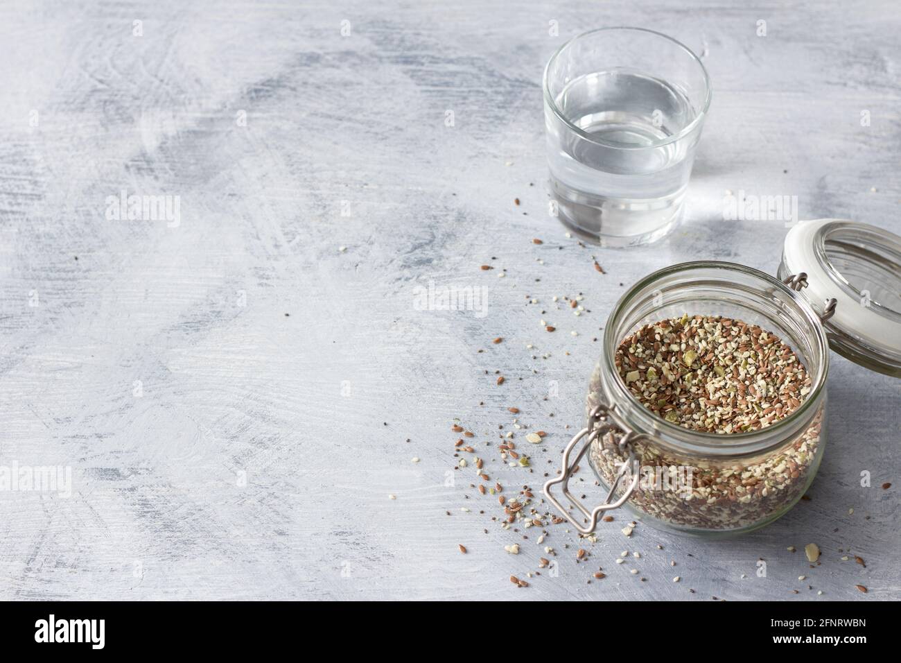Mélange de céréales pour des craquelins keto sains de graines de chia, de lin, de sésame, de graines de citrouille moulues dans un pot en verre sur fond de bois gris, horizontal Banque D'Images