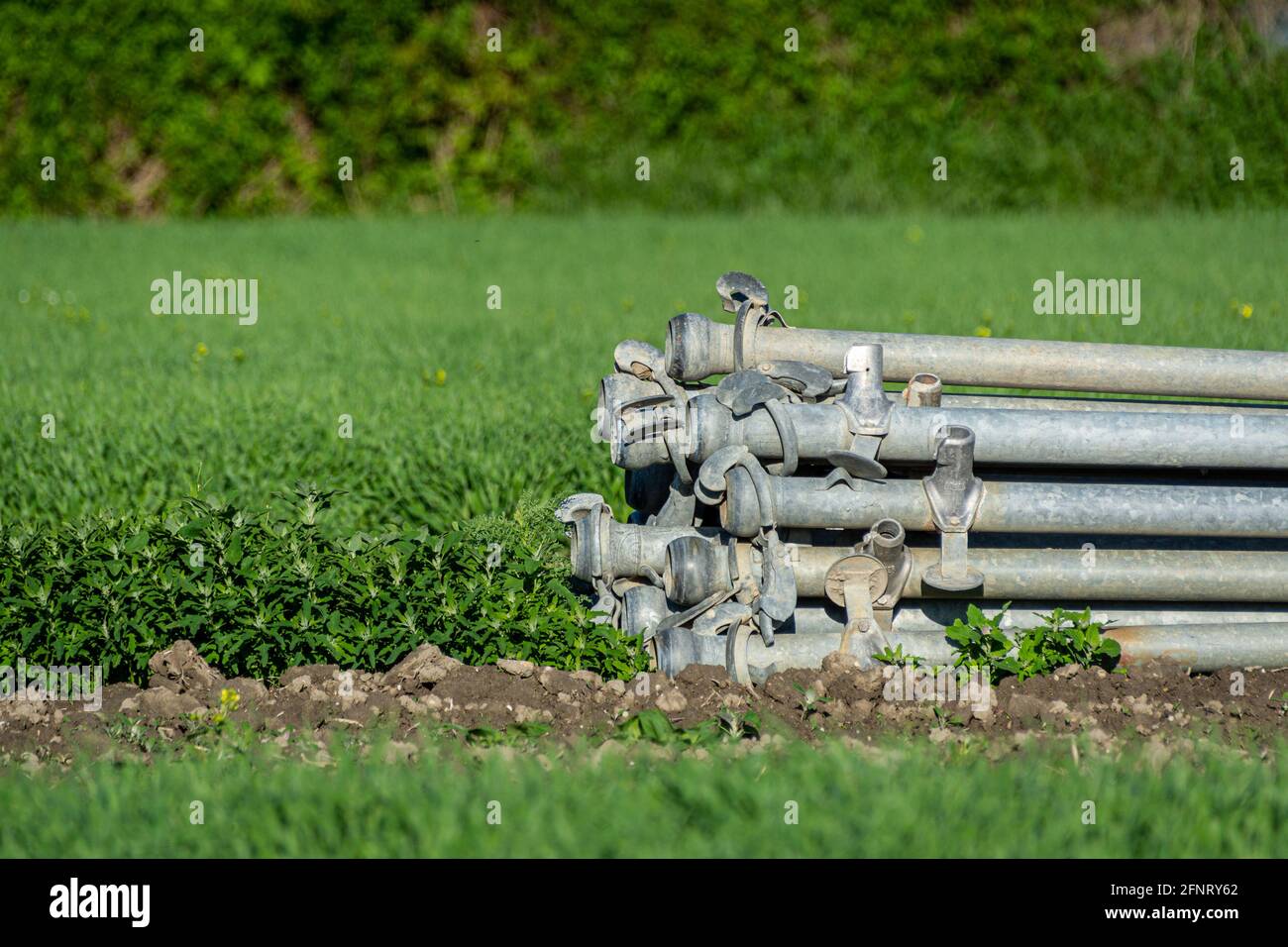 Une pile de tuyaux d'irrigation ronds en métal sur une ferme. Banque D'Images