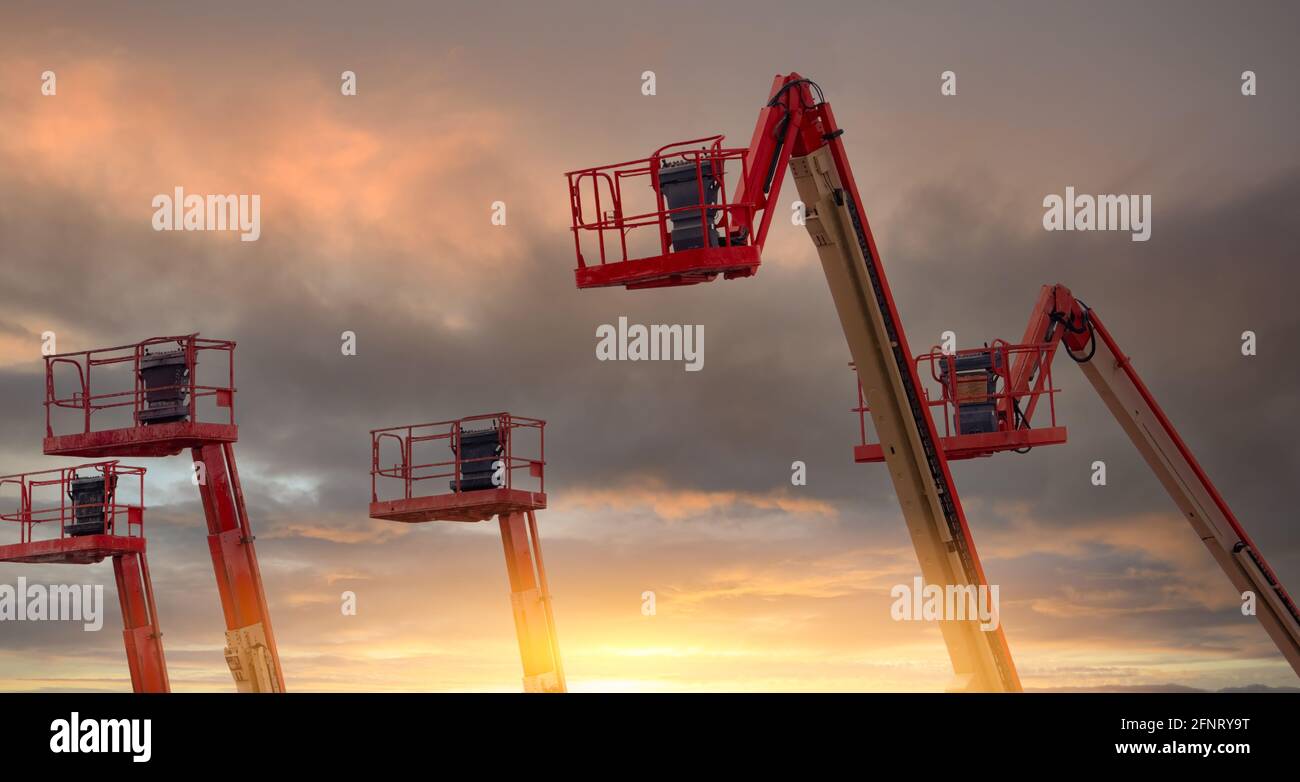 Relevage de la flèche articulée. Levée de plate-forme aérienne. Relevage de la flèche télescopique avec ciel de coucher de soleil. Grue de construction mobile à louer. Réparer le relevage hydraulique de la flèche. Banque D'Images