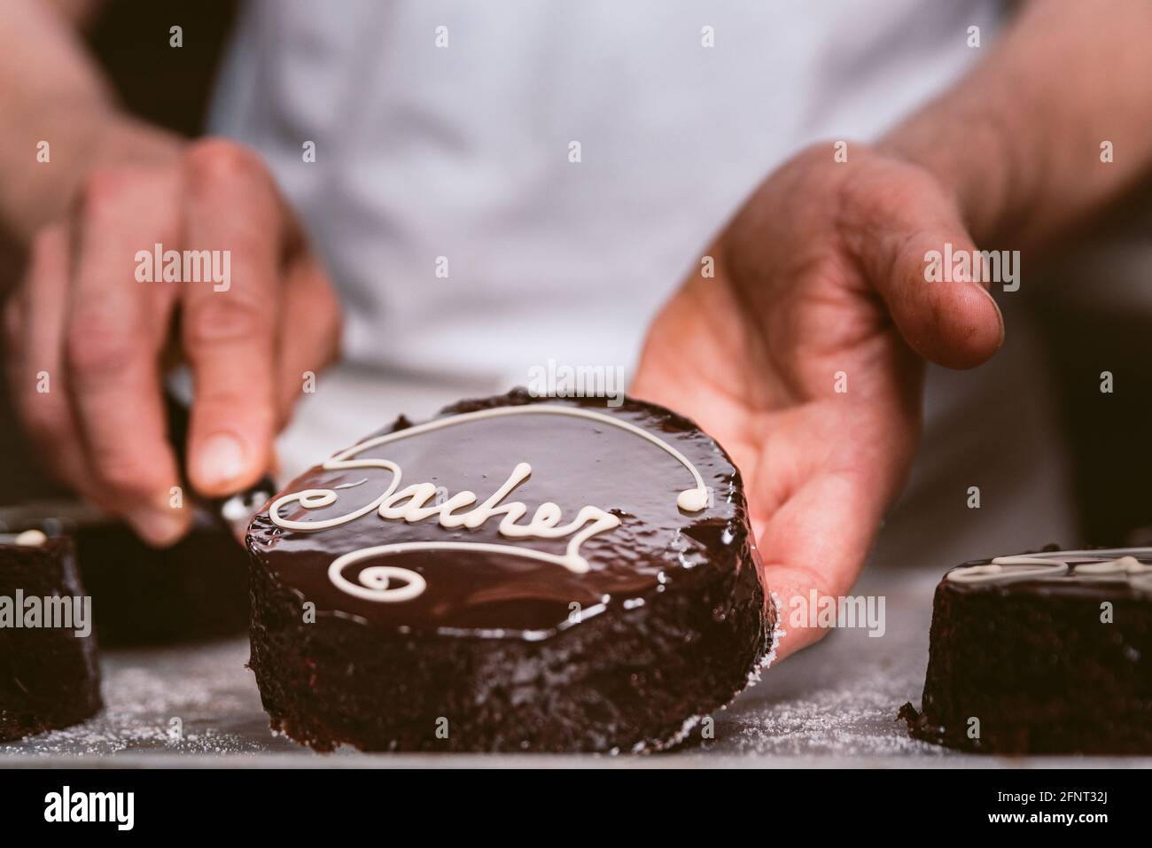 mains tenant le gâteau au chocolat sacher dans la boulangerie. chef pâtissier tenant le gâteau dans le laboratoire pâtissier. concept de la traditionnelle main sachertorte c Banque D'Images