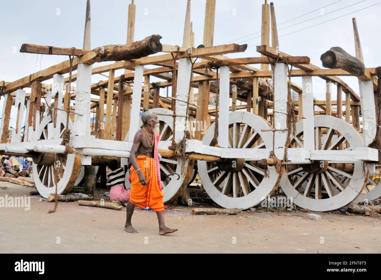 La photo montre un vieil homme qui marche devant le ratha inachevé. La composition de l'image est perfectionnée par la combinaison de l'homme et de rath Banque D'Images