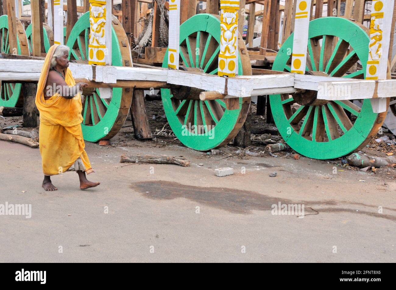 La photo montre une vieille femme qui marche devant le ratha inachevé. Banque D'Images