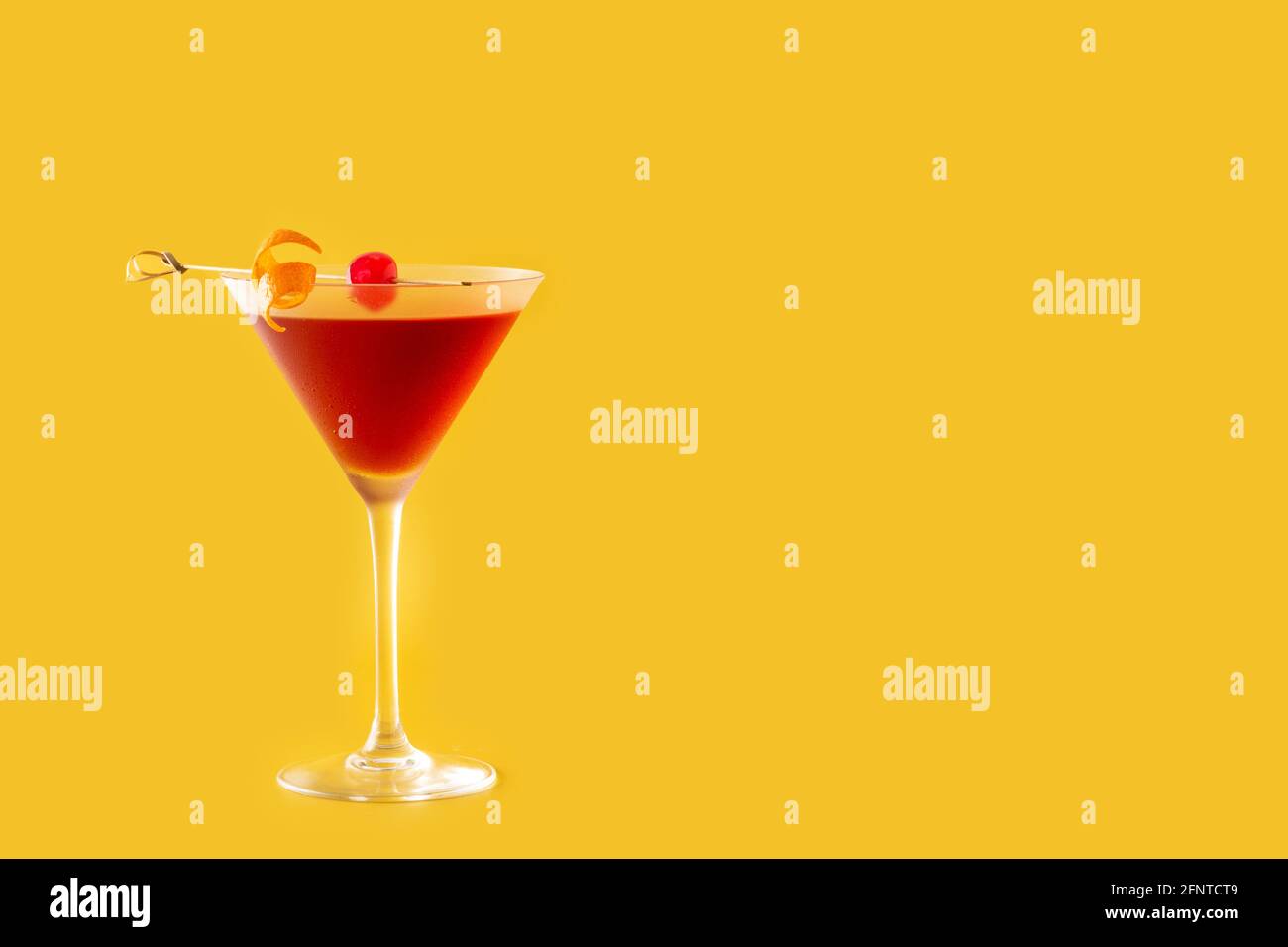 Cocktail traditionnel de Manhattan avec cerise sur fond jaune Banque D'Images