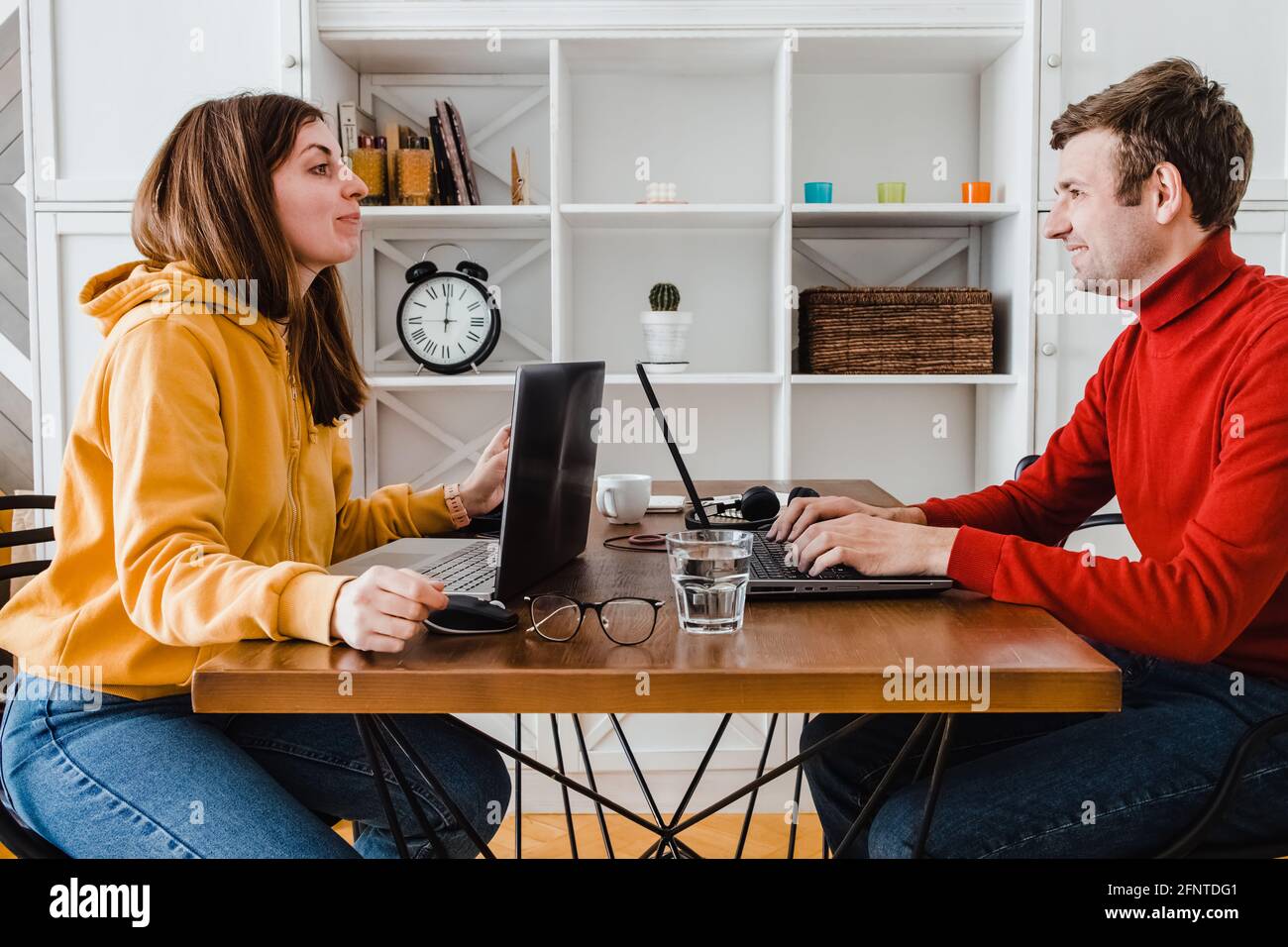 Homme et femme travaillant à la maison dans la même pièce. Rire les uns envers les autres Banque D'Images