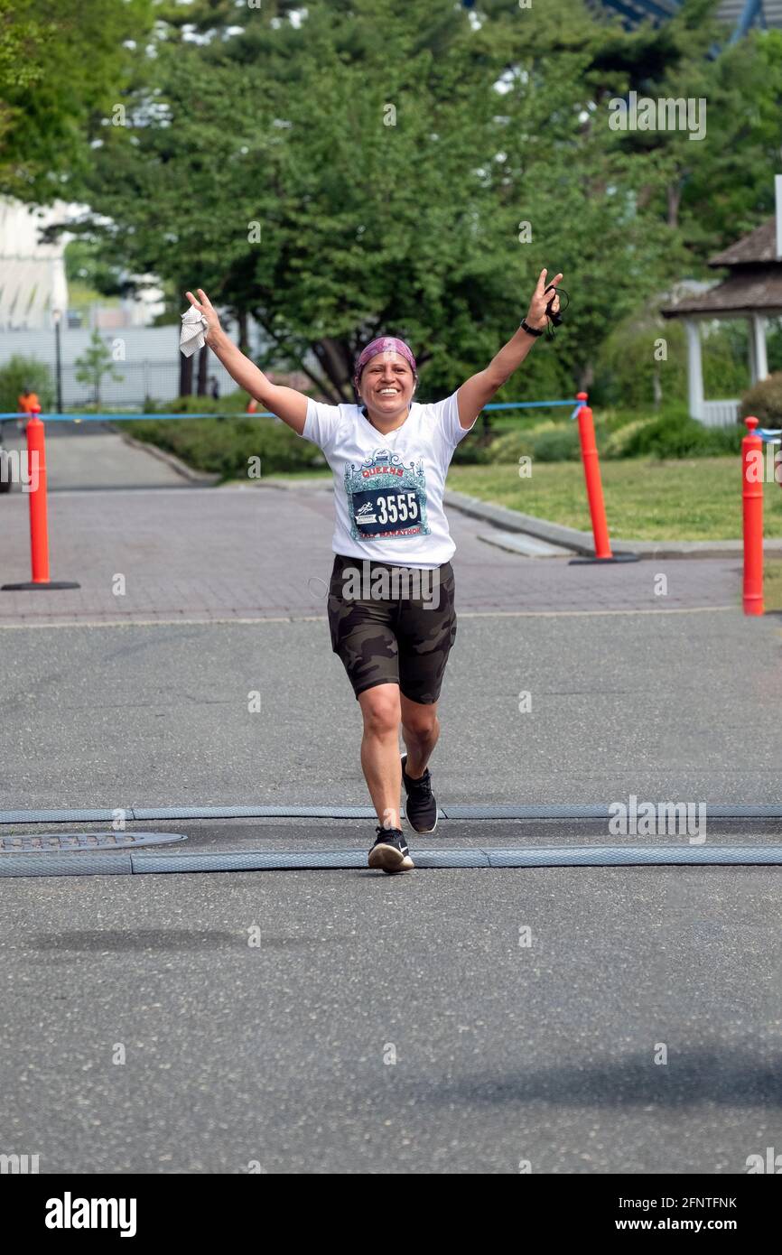 Une jeune femme est jubilante à l'approche de la ligne d'arrivée du semi-marathon du NYCRuns Queens à Flushing Meadows Corona Park à New York. Banque D'Images