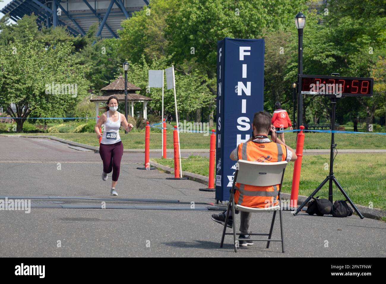 Le photographe officiel de course prend un cliché d'une femme qui approche de la fin du semi-marathon du NYCRuns Queens à Flushing Meadows Corona. Banque D'Images