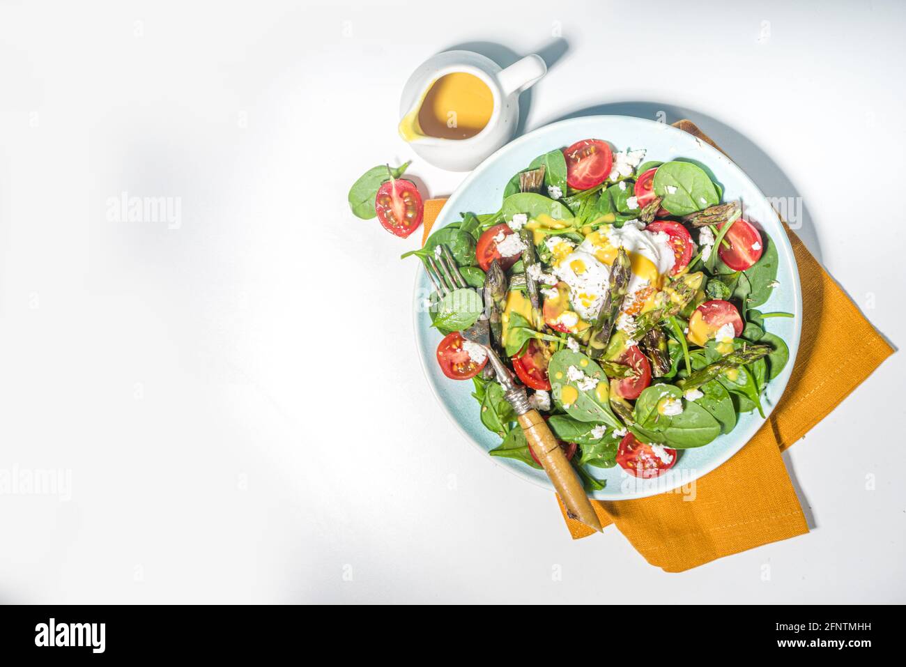 Nourriture saine végétalienne, salade d'asperges chaudes avec des jeunes épinards, tomates cerises, fromage feta et œuf poché, lumière bleue lumière sur fond vue du dessus c Banque D'Images