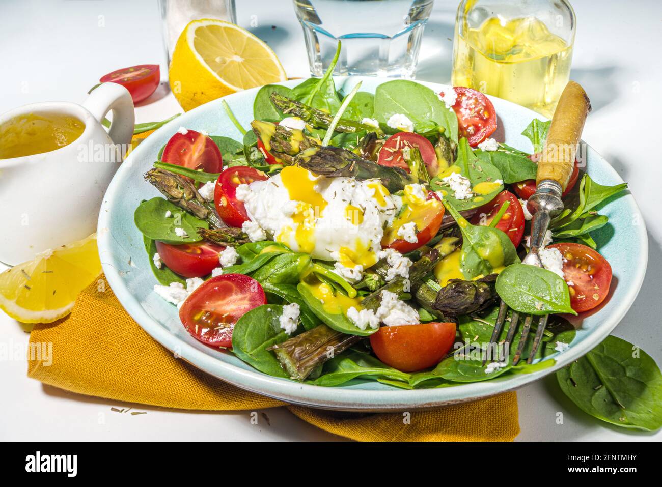 Nourriture saine végétalienne, salade d'asperges chaudes avec des jeunes épinards, tomates cerises, fromage feta et œuf poché, lumière bleue lumière sur fond vue du dessus c Banque D'Images