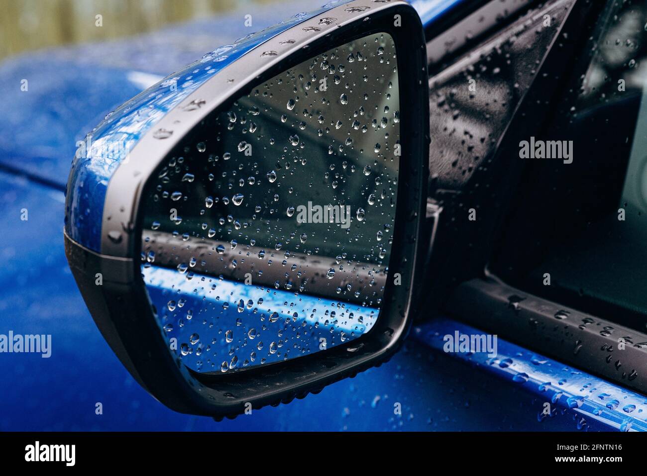 Gouttes de pluie sur un miroir d'une voiture bleue. Automne. Mise au point sélective douce. Banque D'Images