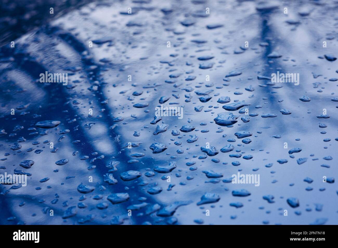 Gouttes de pluie sur la surface d'une voiture bleue. Texture d'automne. Mise au point sélective douce. Banque D'Images