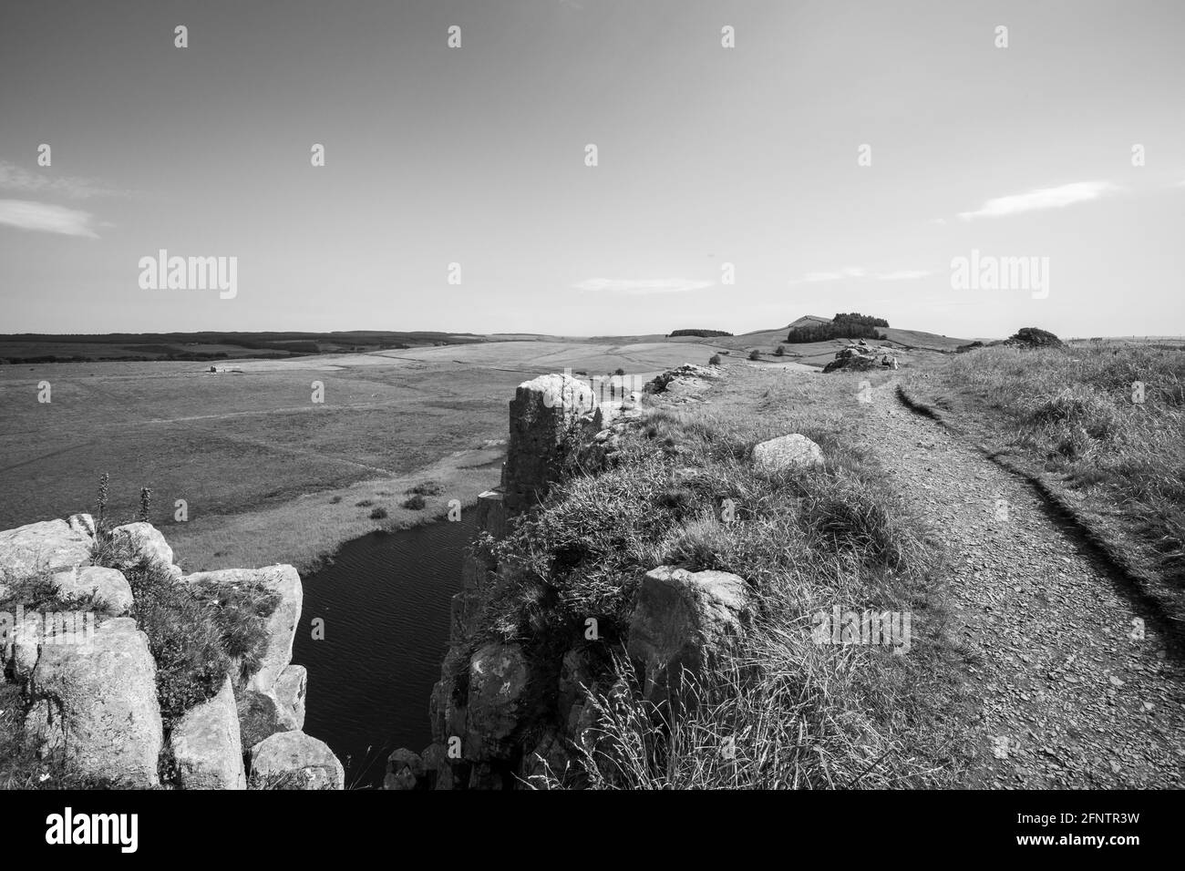 Northumberland UK: Mur Hadrien construit sur de hautes falaises (mur romain) lors d'une journée ensoleillée d'été dans la campagne anglaise. Vue sur le lac Banque D'Images