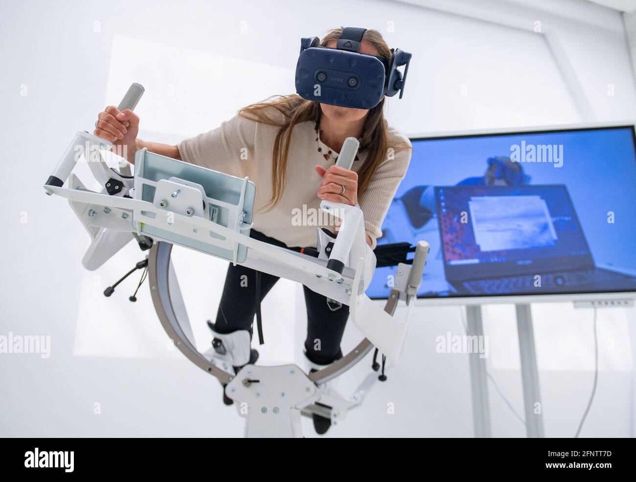 19 mai 2021, Saxe-Anhalt, Halle (Saale): Anja Wolf démontre l'utilisation d'un appareil de fitness spécial avec des lunettes VR pour la recherche dans le nouveau centre de santé numérique Erxleben au centre médical de l'université de Halle. Une nouvelle partie du bâtiment a été ouverte au centre d'apprentissage Dorothea Erxleben du centre médical universitaire. Trois projets différents y sont situés - ils traitent de la question de savoir comment les soins médicaux pour les patients peuvent être améliorés à l'aide des méthodes de technologie de l'information. Credit: dpa Picture Alliance/Alay Live News Banque D'Images