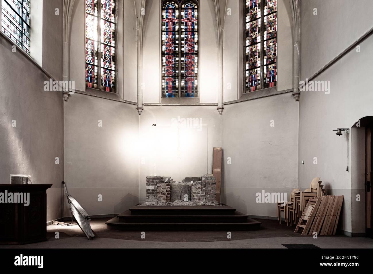 Intérieur dédié à l'église avec un autel déchiré et de hautes fenêtres colorées de l'église Banque D'Images