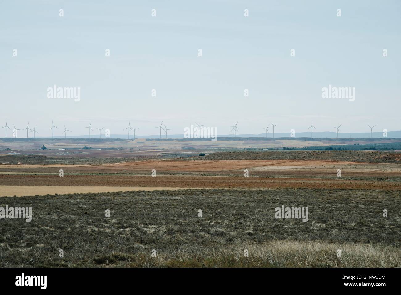 Une vue sur un paysage sec de Los Monegros à Aragon, Espagne, avec une ligne d'éoliennes en arrière-plan Banque D'Images